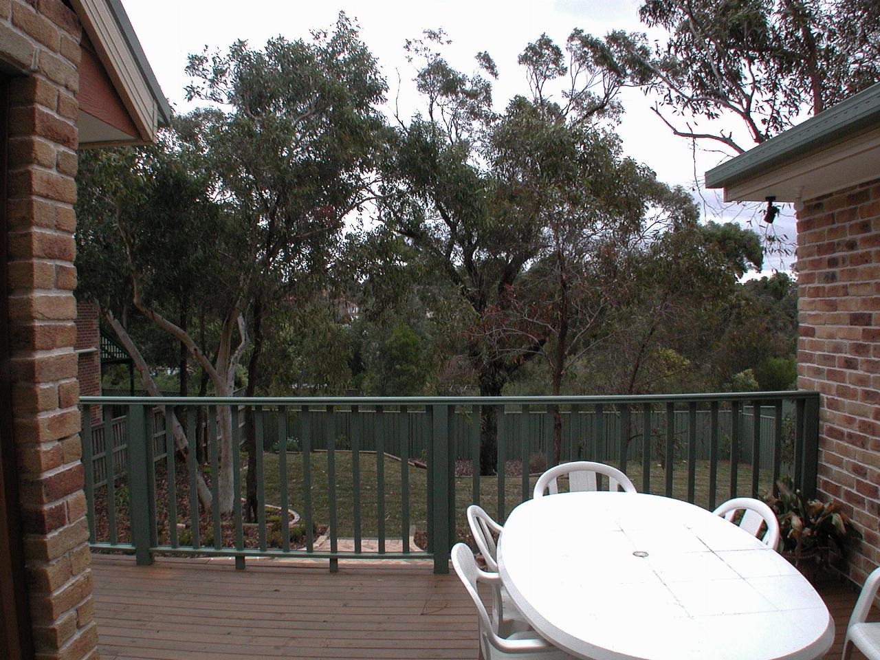 Back deck with outdoor table and chairs overlooking bush setting