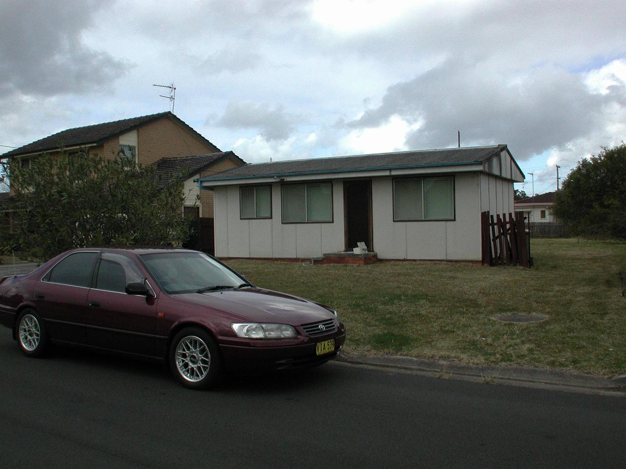 Red Camry parked outside small fibro cottage