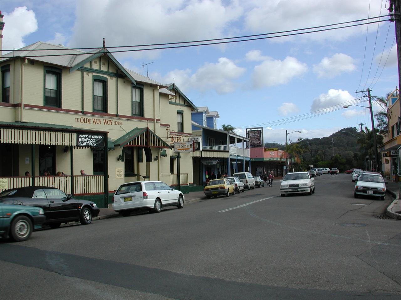 Cream with green trim hotel with cars parked along the street