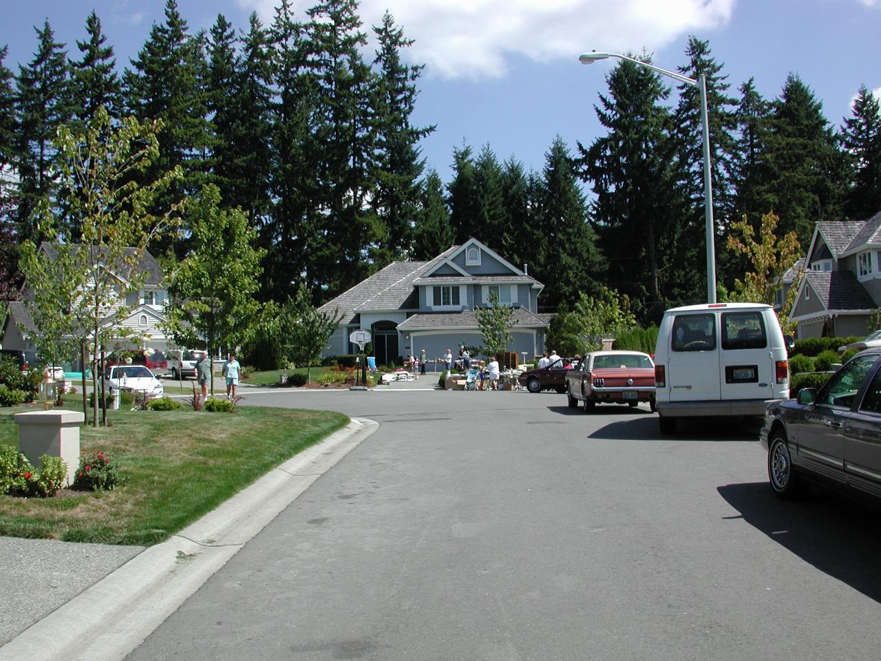 Street scene with cars and people looking at goods for sale