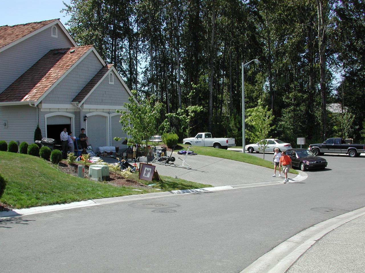 Street scene with cars and people looking at goods for sale