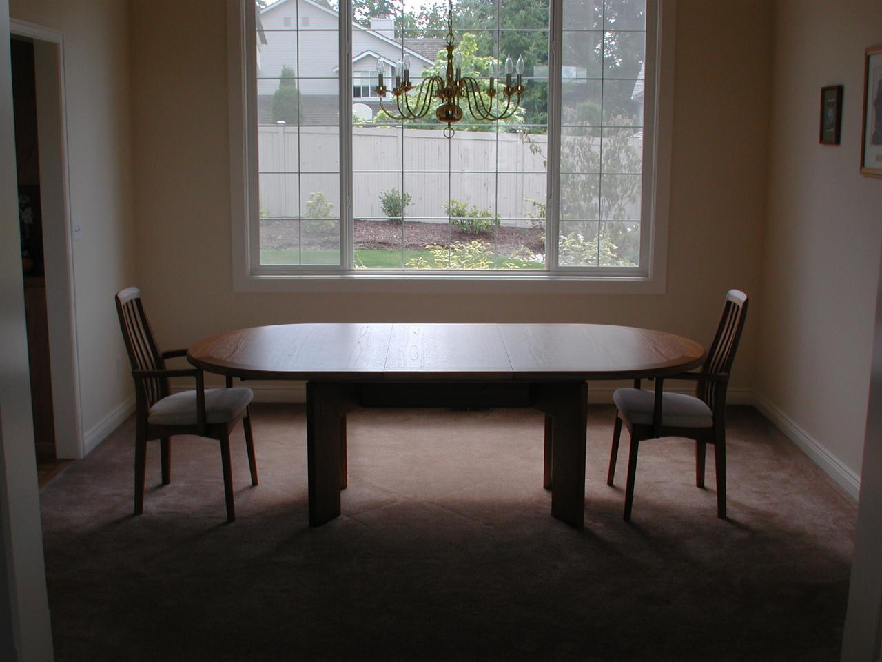 Dining table and two chairs, window to back year behind