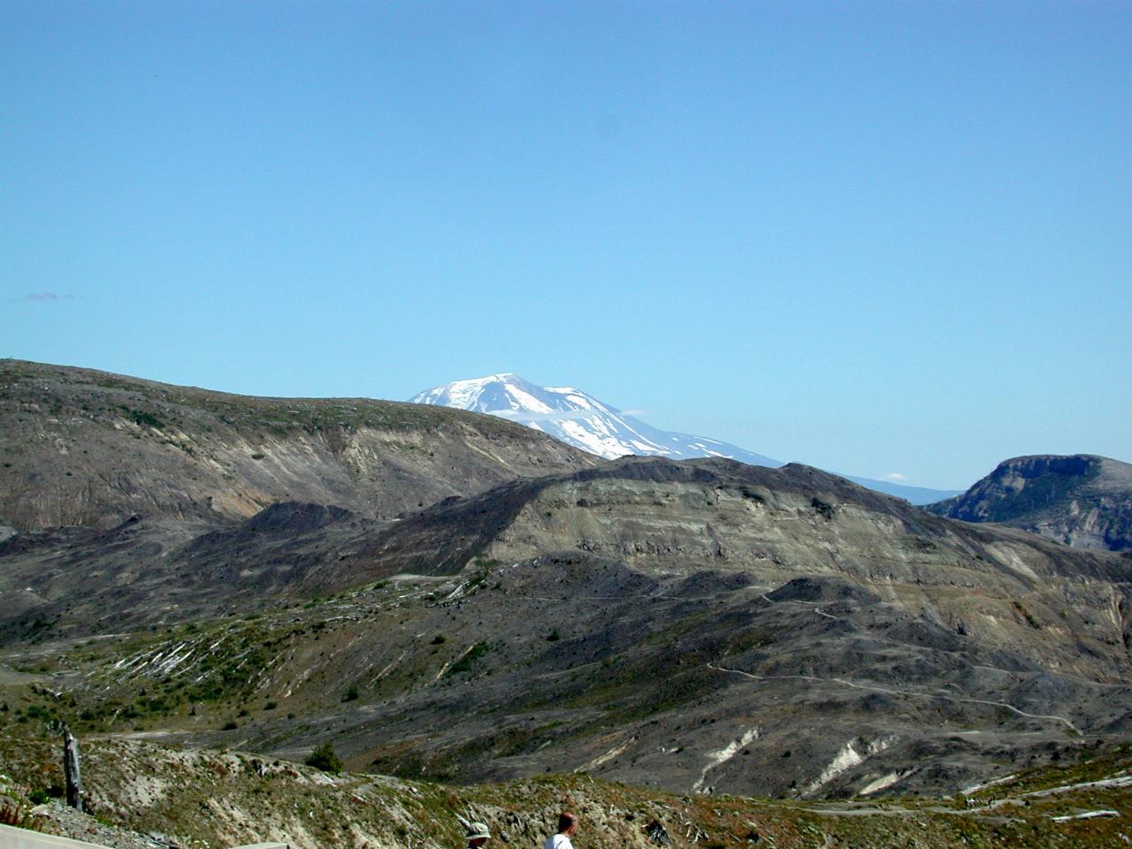 Snow covered volcanic peak just visible over top of nearby hills