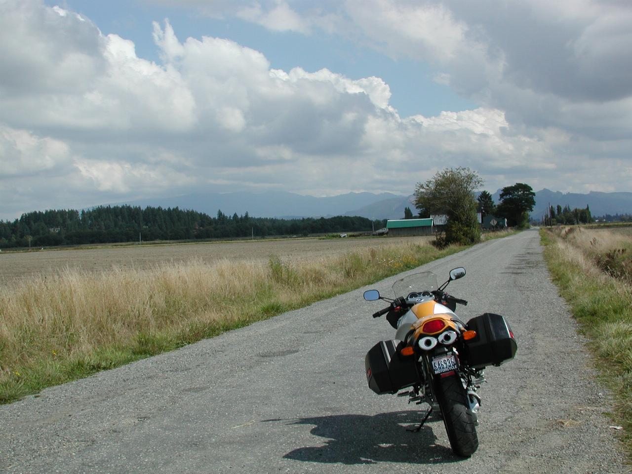 Motorcycle parked at end of road, looking towards mountains