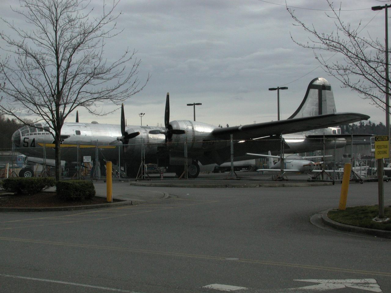 Four engined WW II bomber behind chain link fence