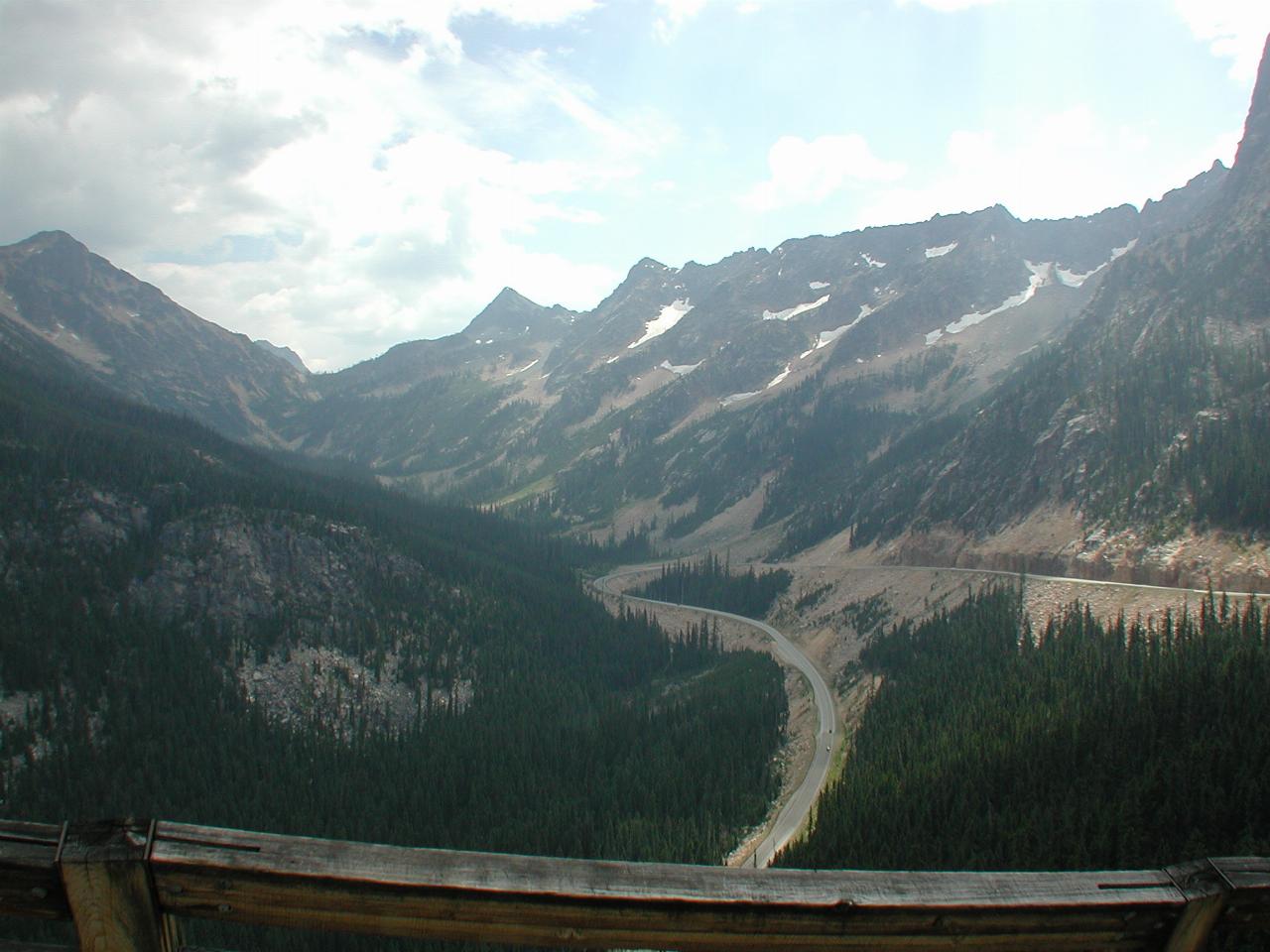 Mountaineous terrain, rocky with treed areas and winding road