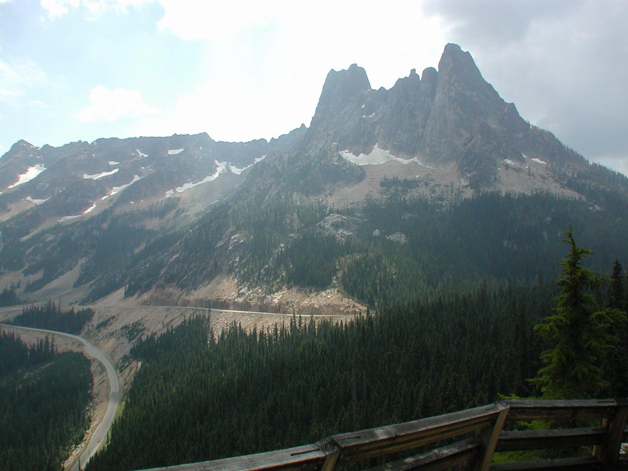 Mountaineous terrain, rocky with treed areas and winding road