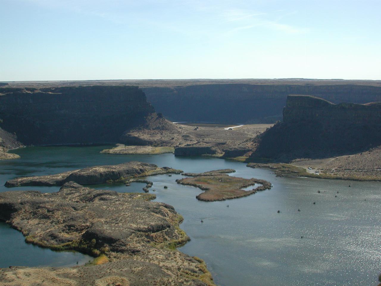 Dry Falls - the lakes where the water eroded the bottom - note cars in mid right and man in boat, lower centre