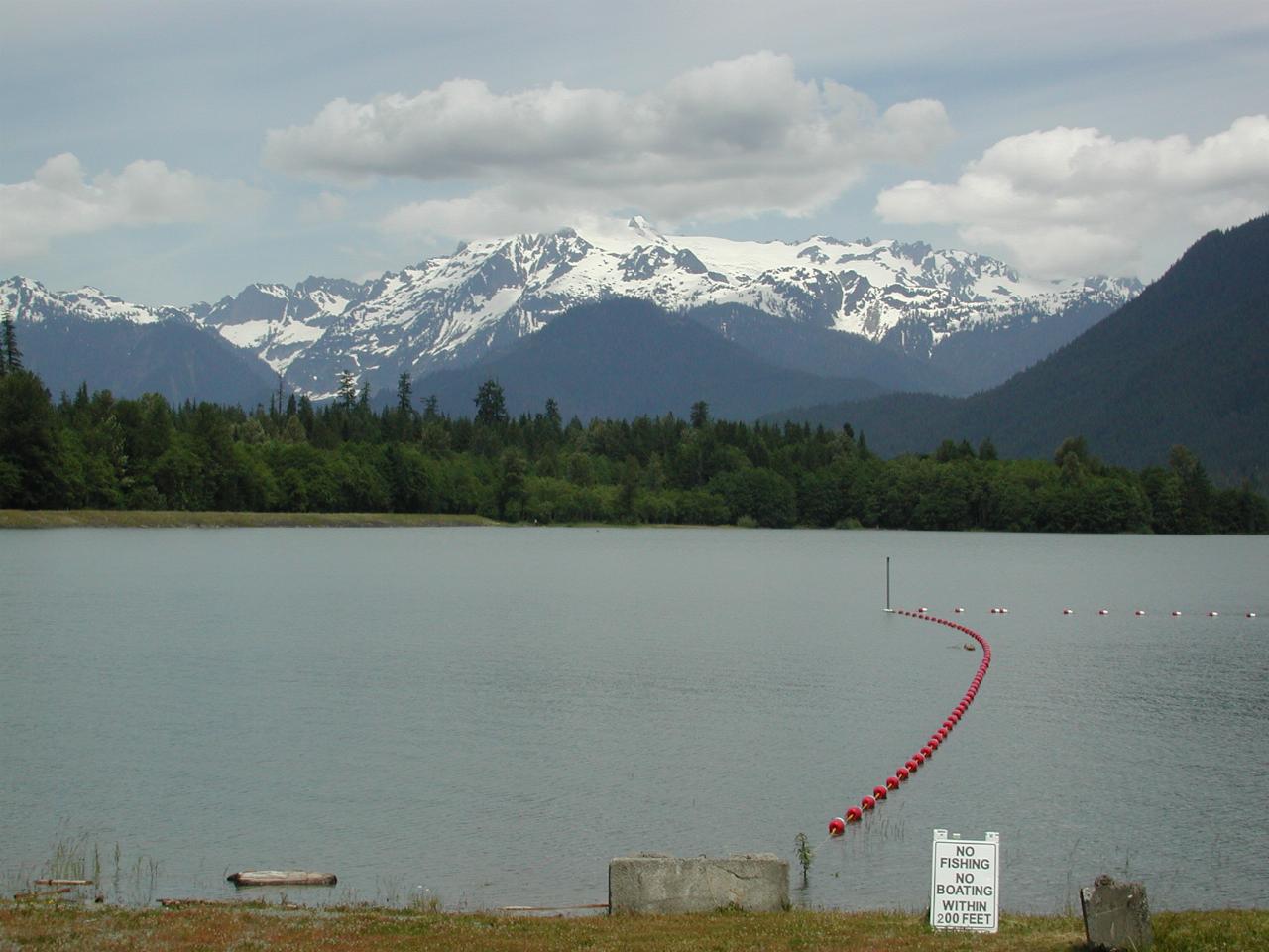 Mt. Shuksan, obsucred by clouds, viewed over a full Baker Lake