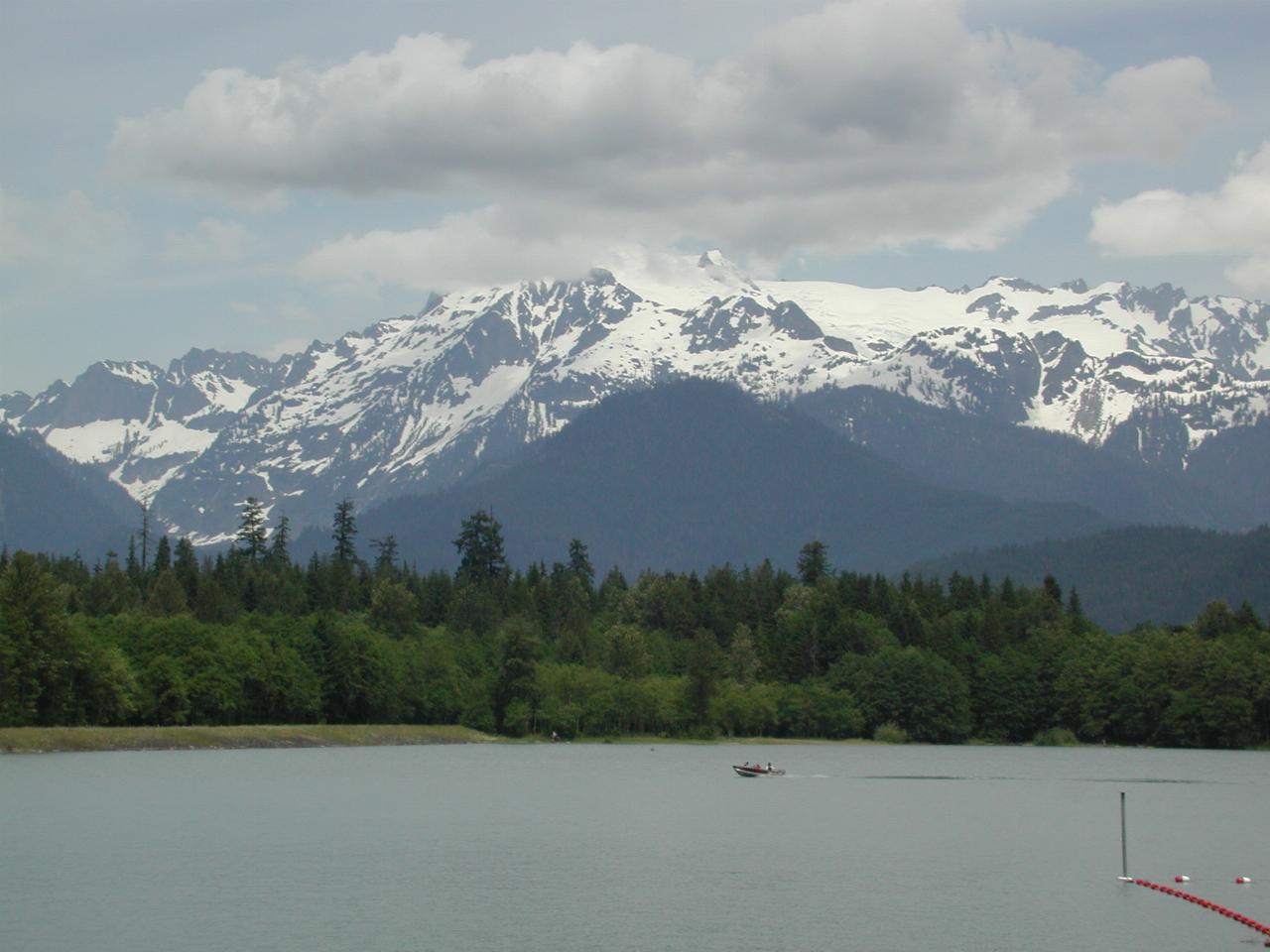 Mt. Shuksan, obsucred by clouds, viewed over a full Baker Lake