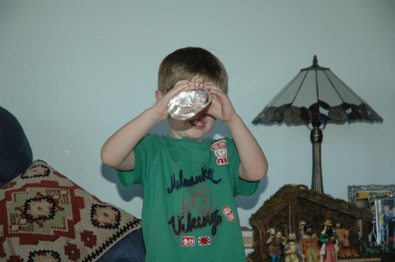 Jake looking through a bottle at the photographer during Christmas tree decorating at Illawong