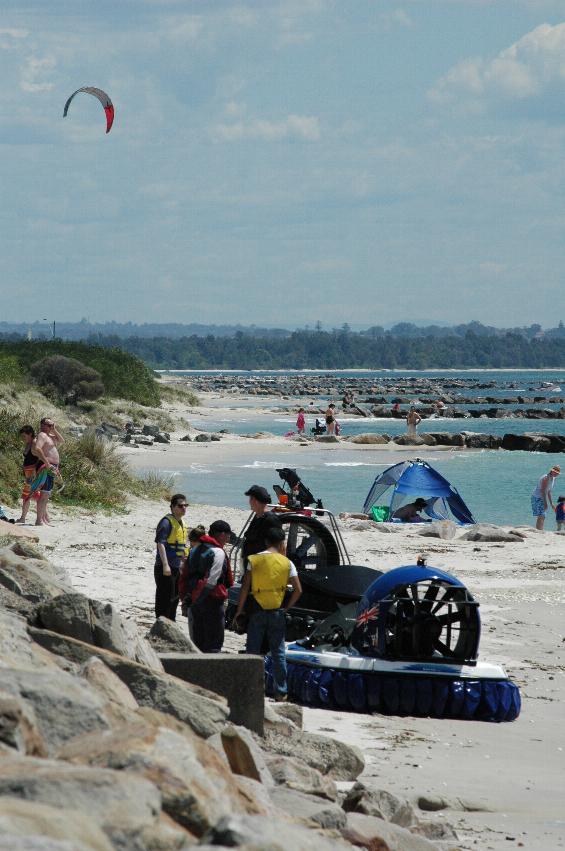 Hovercraft on beach with paraglider in the background, looking west