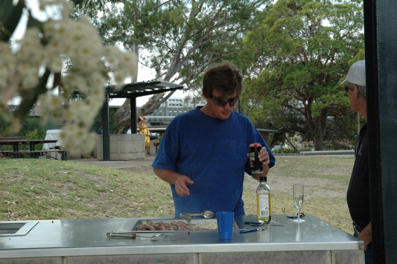 Cameron in cooking mode, with Peter at barbeque at Como Pleasure Grounds as train passes on Como Bridge