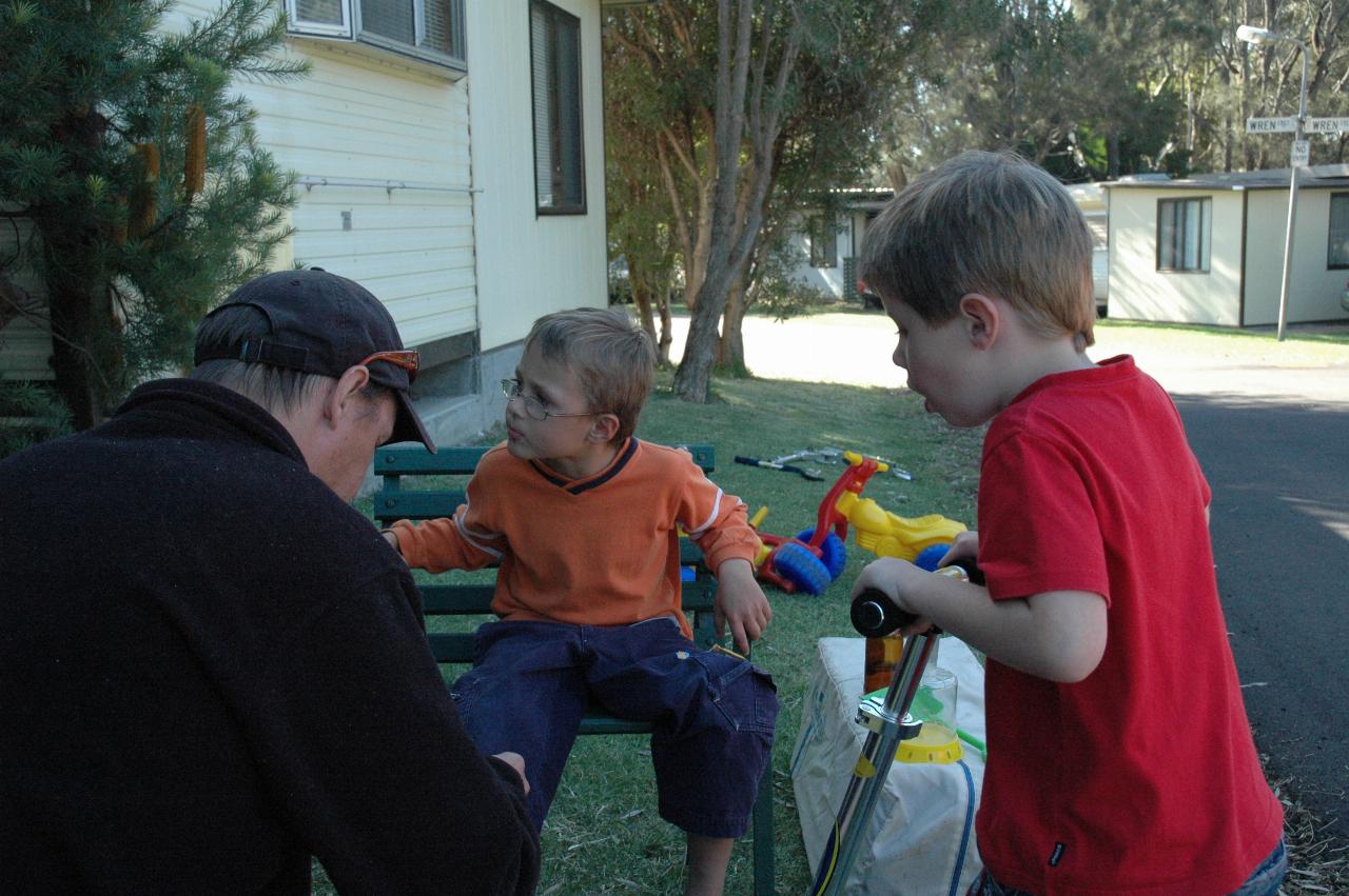 Glenn doing up Tynan's shoe at Bendalong, Easter while Jake looks on