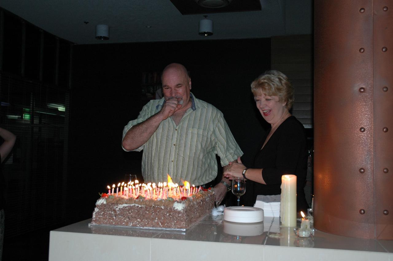 Peter drawing breath to blow out the 50 candles at his party at Fenner Hall, ANU