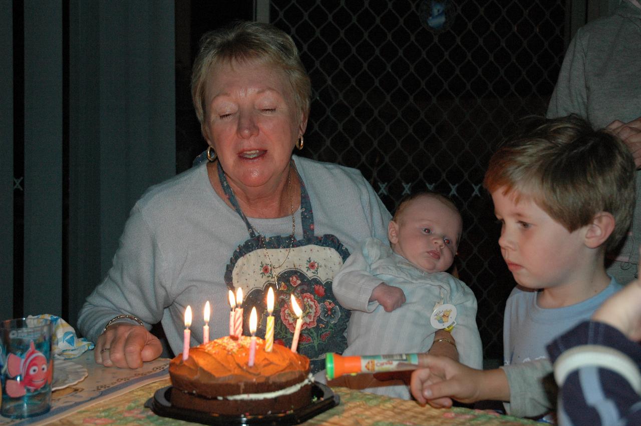 Yvonne blowing out the candles on the cake, with Baby Cooper Wallace and Jake Crofts looking on