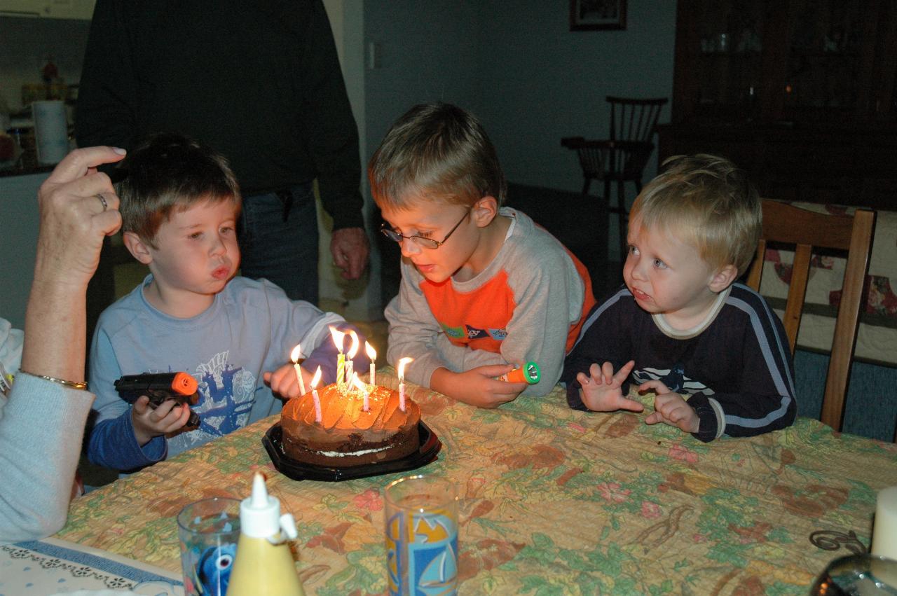 Jake Crofts and Tynan Wallace starting to blow out the candles on Yvonne's birthday cake