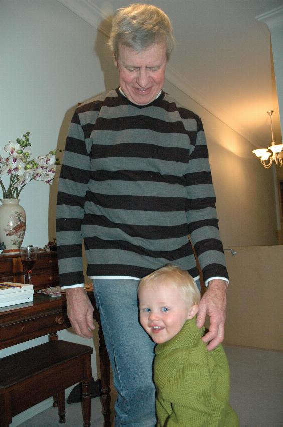 Baby hanging onto grandfather's leg