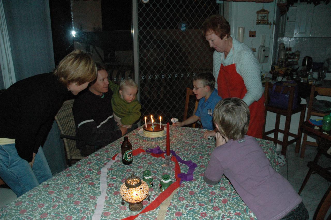 Family gathered around father and baby in front of cake