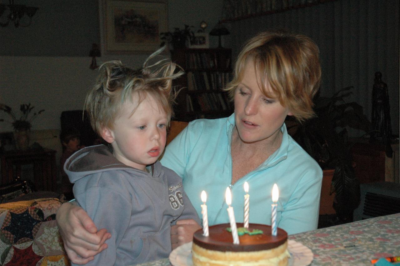 Zombie child sitting on his mothers lap in front of cake with lit candles