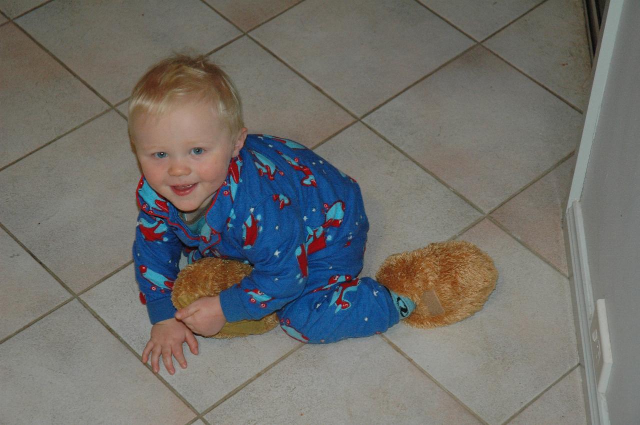 Baby in blue pyjamas on landing, looking at camera