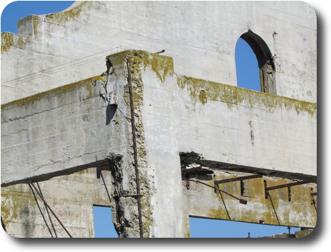 Section of concrete building showing damage from the elements exposing reinforcing rods