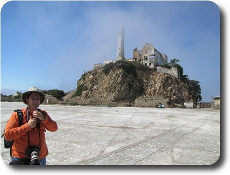 Photographer on concrete area, hill with lighthouse and building shell behind