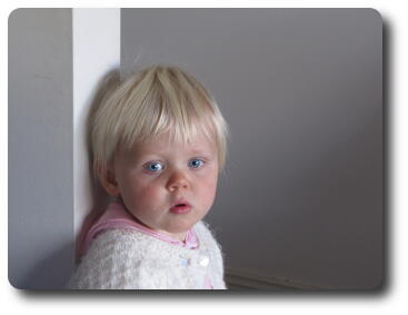 Little girl back to wall looking sideways to camera