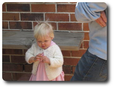 Little girl in front of wooden bench attached to wall