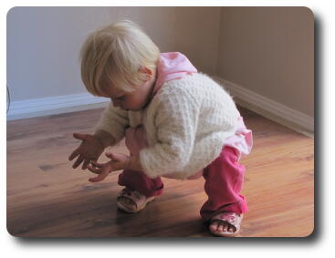 Little girl crouching, looking at her open hands