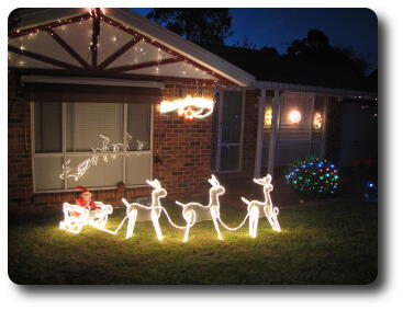 Santa in sleigh with reindeer, all outlined in lights