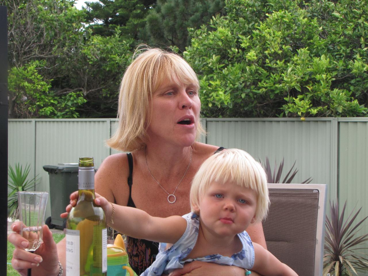 Little girl on mum's lap reaches bottle