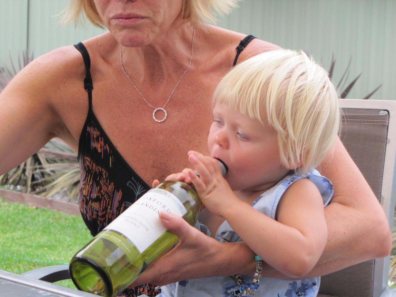 Little girl with empty wine bottle to mouth