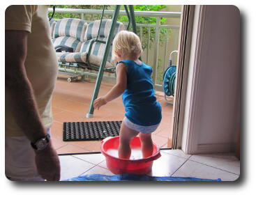 Little girl with feet in red bucket with soapy water