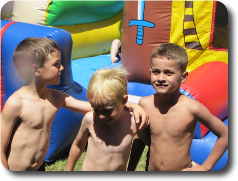 Three young boys in front of inflatable jumping castle