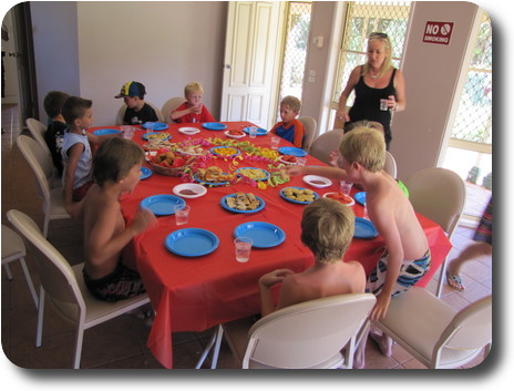 Boys around dining table, helping themselves to party food