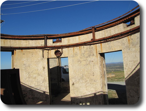 Inside view of circular telescope building, rusted steel track around top for dome