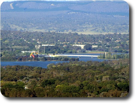 View over bush, then water to museum building