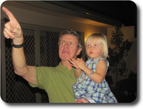 Grandfather pointing while holding granddaughter in arms