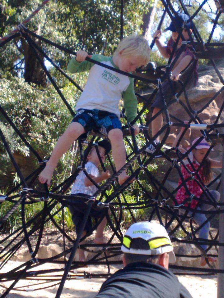 Little boy looking as he climbs down on the ropes