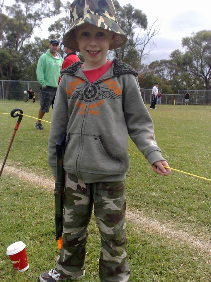 Young boy dressed in fatigues carrying gun