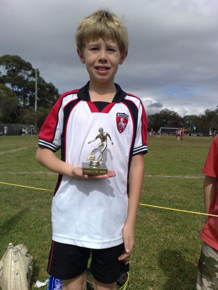 Young boy in soccer outfit holding a trophy