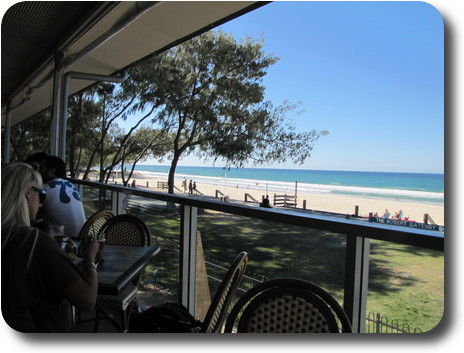 Dining chairs on balcony overlooking golden beach and very blue water