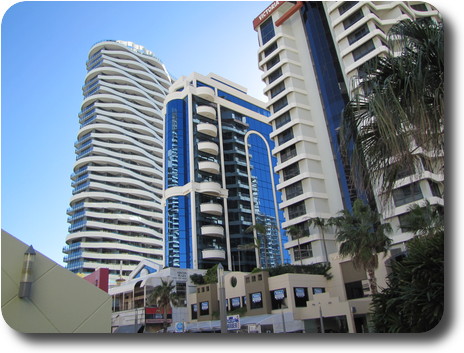 Tall buildings; one with wavy balconies, one with reflective glass, one ordinary