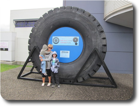 Mother and sons in front of very large tyre