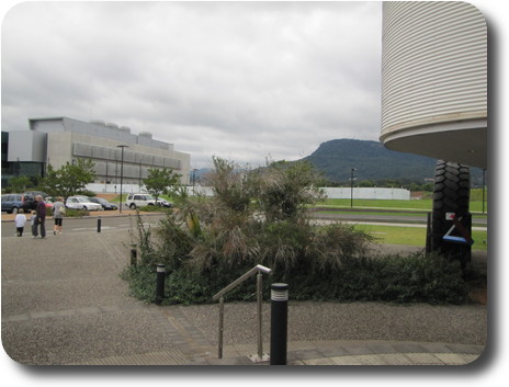 Tree covered mountain between low buildings, and party walking back to car