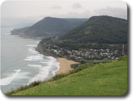 Looking over cliff to beach, houses and cliffs disappearing in the mist