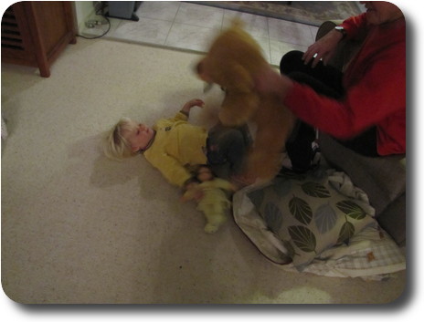 Little girl on floor, adult holding bear to 