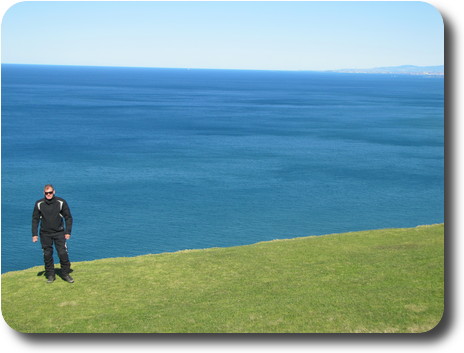 Man standing on cliff edge, looking back to camera