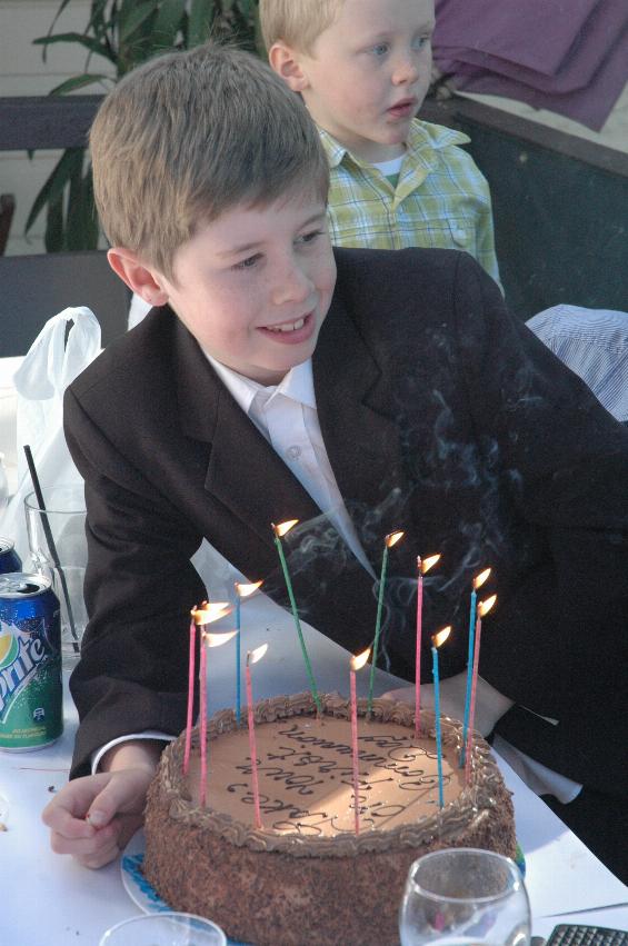 Boy behind chocolate cake with candles